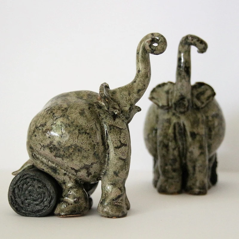 small ceramic elephants sitting on a log