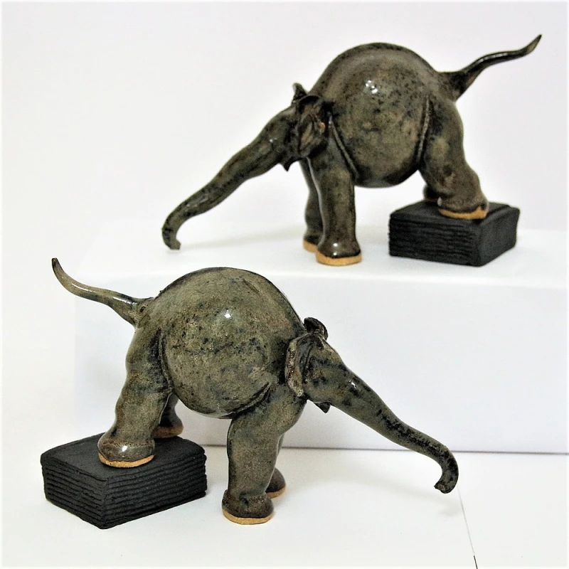 small ceramic elephants standing on books