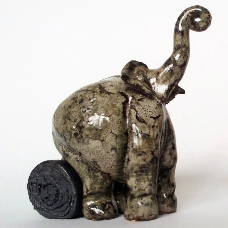 small ceramic elephant sitting on a log
